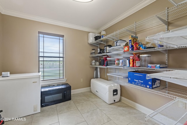 laundry area with crown molding and light tile patterned floors