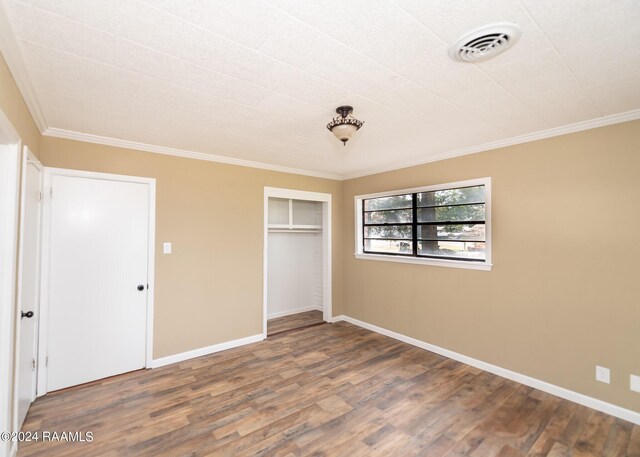 unfurnished bedroom with wood-type flooring, a closet, and crown molding