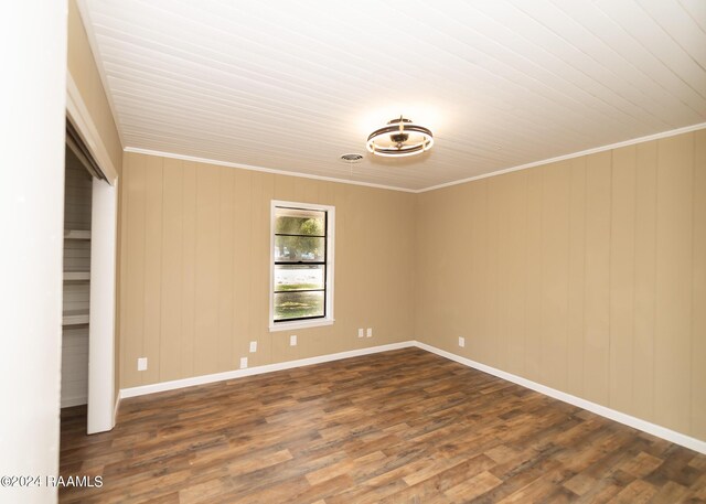 empty room with wooden walls, dark hardwood / wood-style floors, and crown molding