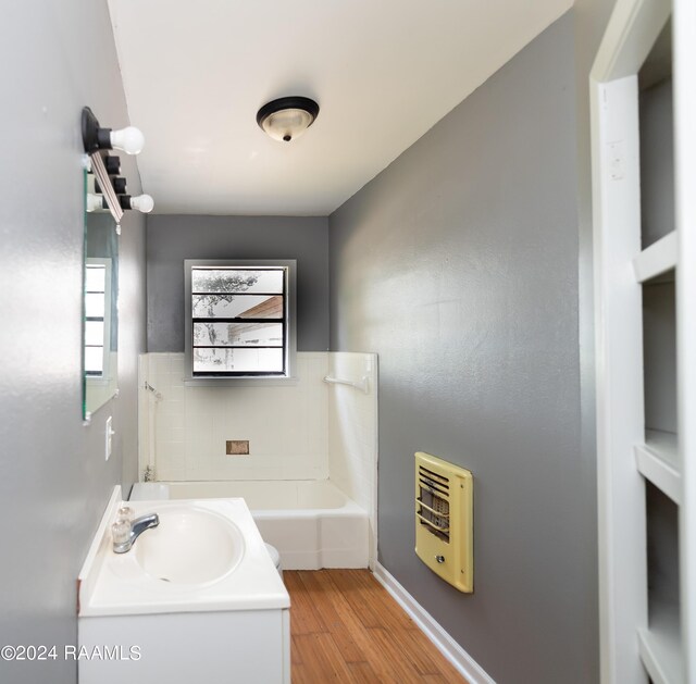 bathroom featuring vanity, heating unit, washtub / shower combination, and wood-type flooring