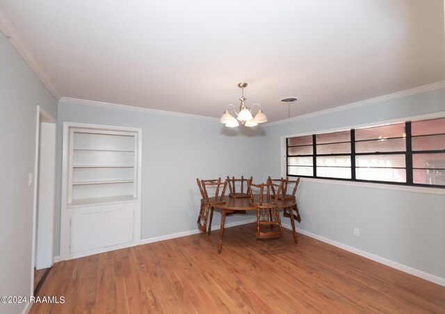 dining room with ornamental molding, wood-type flooring, a chandelier, and built in shelves