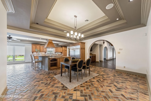 dining room featuring ceiling fan with notable chandelier, crown molding, and a raised ceiling