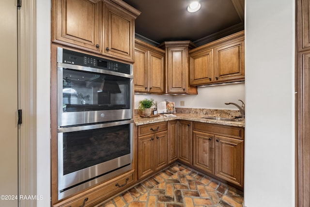 kitchen featuring light stone countertops, double oven, and sink