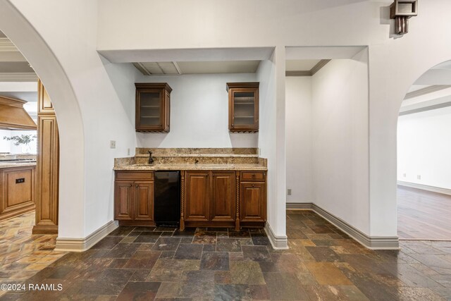 kitchen featuring crown molding, dishwasher, light stone countertops, and sink