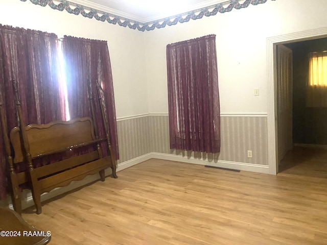 spare room with ornamental molding and light wood-type flooring