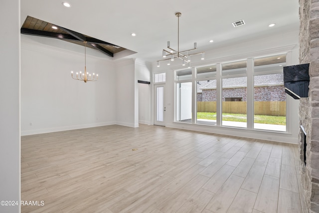 unfurnished living room with a stone fireplace, a notable chandelier, light wood-type flooring, and ornamental molding