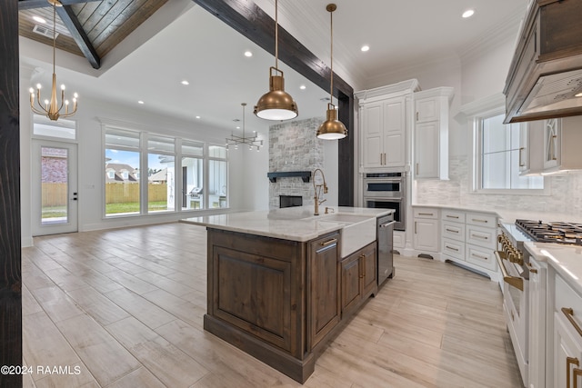 kitchen with a kitchen island with sink, decorative light fixtures, white cabinetry, and stainless steel appliances