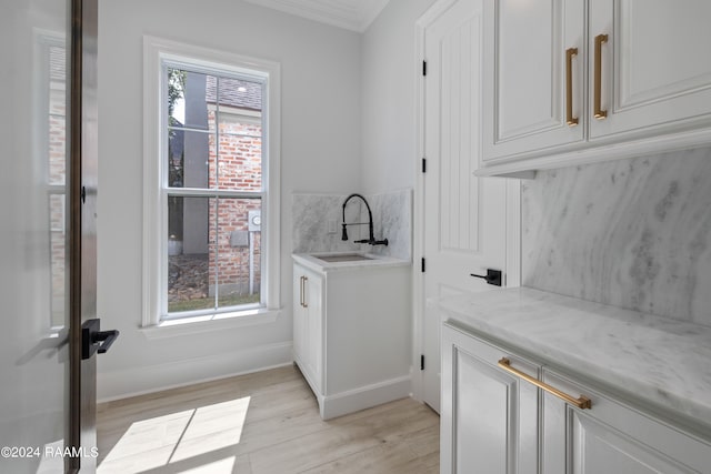 washroom featuring ornamental molding, light hardwood / wood-style flooring, sink, and a wealth of natural light