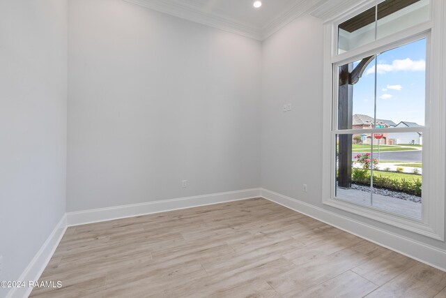 empty room with light wood-type flooring and crown molding