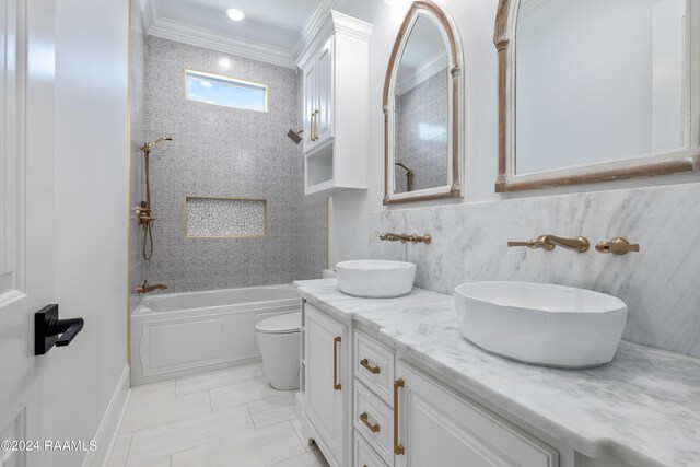 full bathroom featuring ornamental molding, toilet, vanity, and tiled shower / bath combo