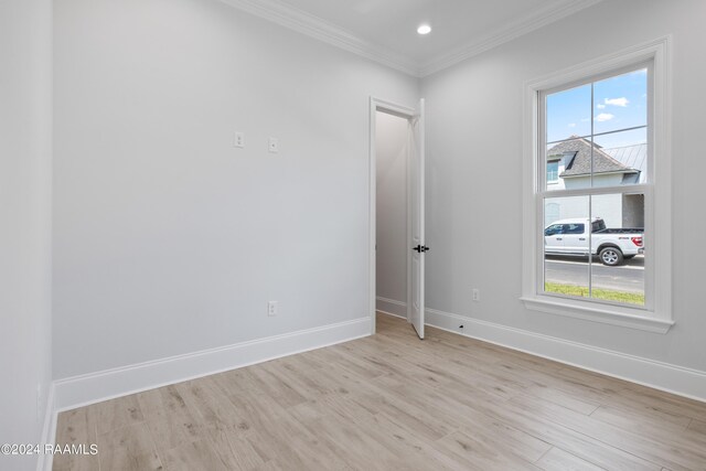 spare room with light wood-type flooring and crown molding