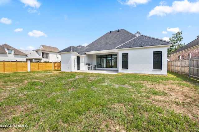 back of house with a lawn and a patio