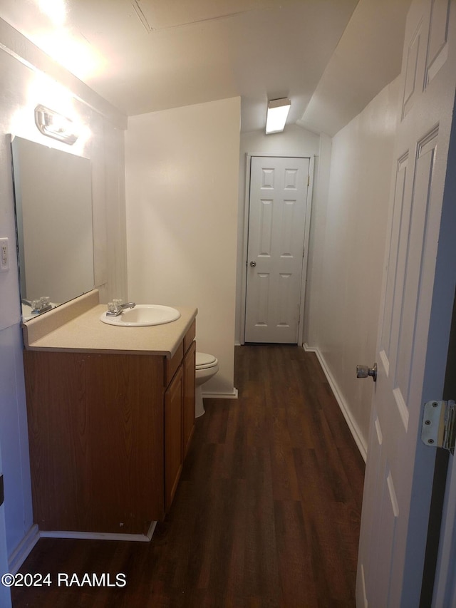 bathroom featuring hardwood / wood-style floors, lofted ceiling, vanity, and toilet