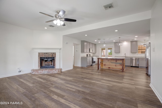 unfurnished living room featuring ceiling fan, a fireplace, dark wood-type flooring, and sink