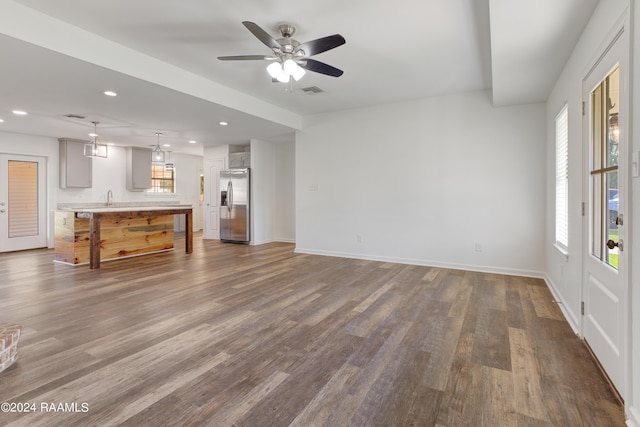 unfurnished living room with dark hardwood / wood-style floors, ceiling fan, and sink