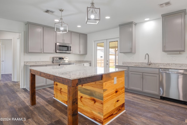 kitchen featuring gray cabinetry, stainless steel appliances, hanging light fixtures, and dark hardwood / wood-style flooring