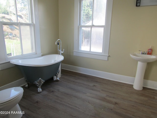 bathroom with wood-type flooring, sink, a washtub, and toilet