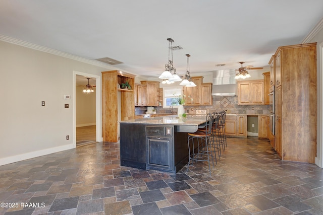 kitchen featuring backsplash, a kitchen breakfast bar, wall chimney range hood, ornamental molding, and a kitchen island