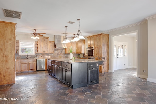 kitchen featuring dishwasher, a center island, sink, wall chimney range hood, and a breakfast bar area