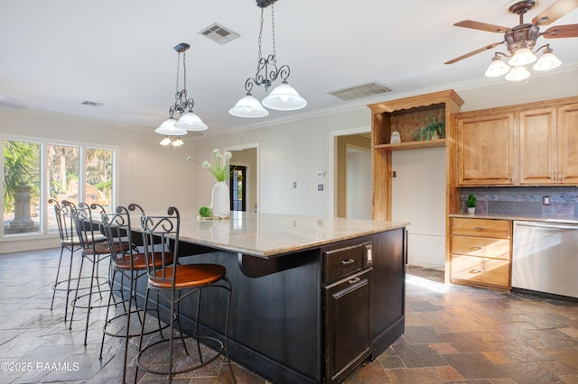 kitchen featuring dishwasher, light stone counters, backsplash, crown molding, and a kitchen island