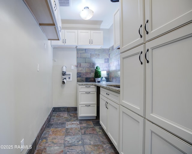 kitchen featuring white cabinets, light stone countertops, crown molding, and tasteful backsplash