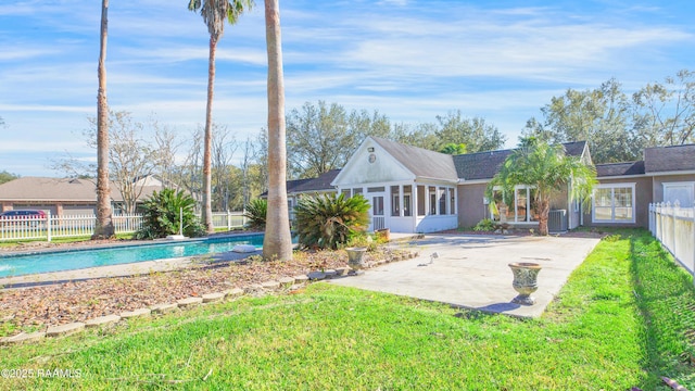 rear view of house with a lawn, a sunroom, a fenced in pool, central air condition unit, and a patio area