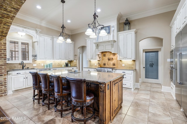 kitchen featuring hanging light fixtures, white cabinetry, light stone countertops, a chandelier, and a center island