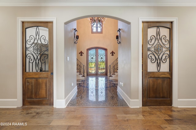 entryway featuring french doors, a chandelier, wood-type flooring, and crown molding