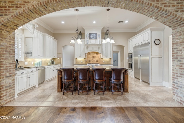 kitchen with light hardwood / wood-style flooring, hanging light fixtures, a center island, and built in appliances