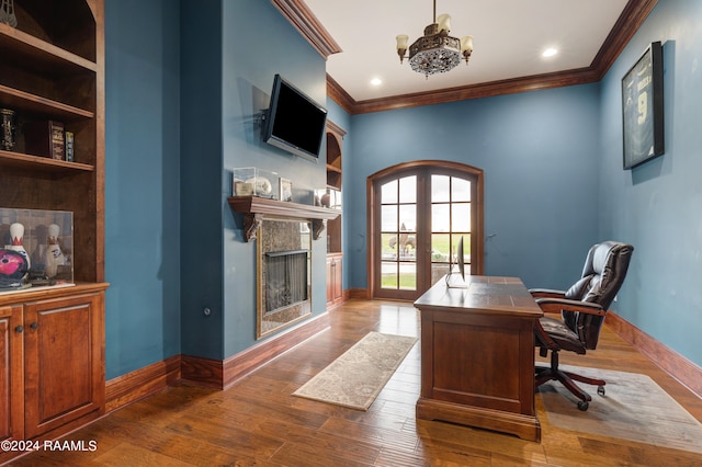 office area featuring french doors, dark wood-type flooring, crown molding, a notable chandelier, and a fireplace