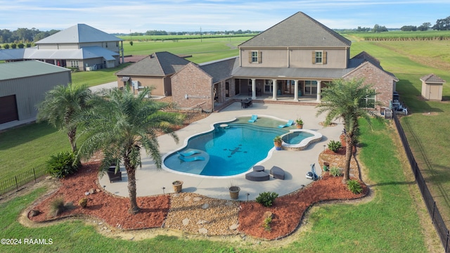 view of pool featuring a patio, an in ground hot tub, a lawn, and an outdoor structure