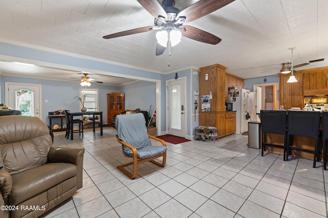 tiled living room with ceiling fan and crown molding