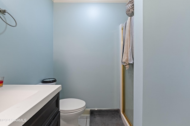 bathroom with vanity, a shower with shower door, tile patterned floors, crown molding, and toilet