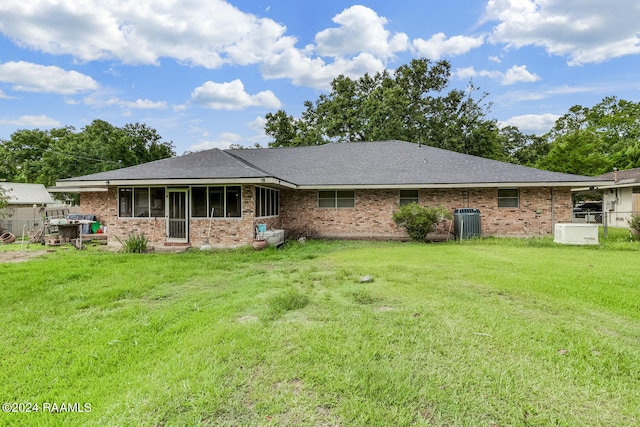 rear view of property with a sunroom, a yard, and central AC