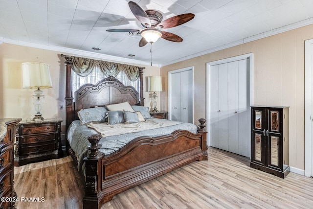 bedroom featuring ceiling fan, multiple closets, light hardwood / wood-style flooring, and crown molding