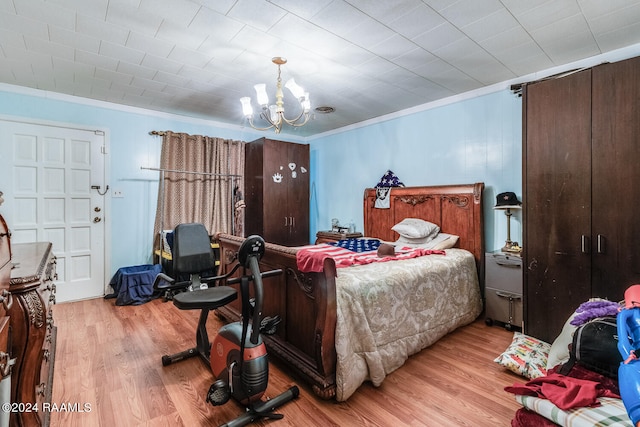 bedroom featuring crown molding, light hardwood / wood-style floors, and a chandelier