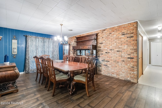 dining space with brick wall, dark hardwood / wood-style floors, and a chandelier