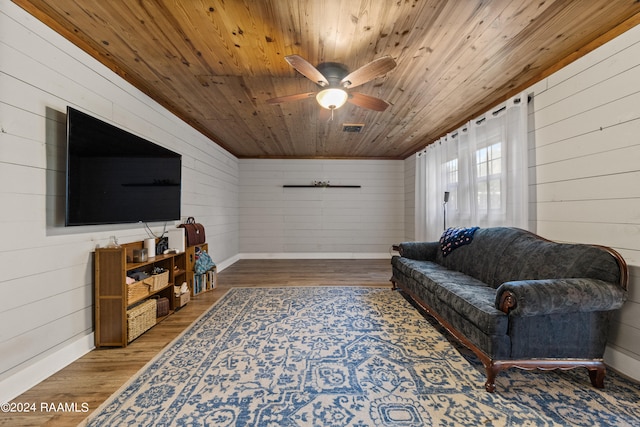 living room featuring wooden ceiling, wooden walls, hardwood / wood-style floors, and ceiling fan