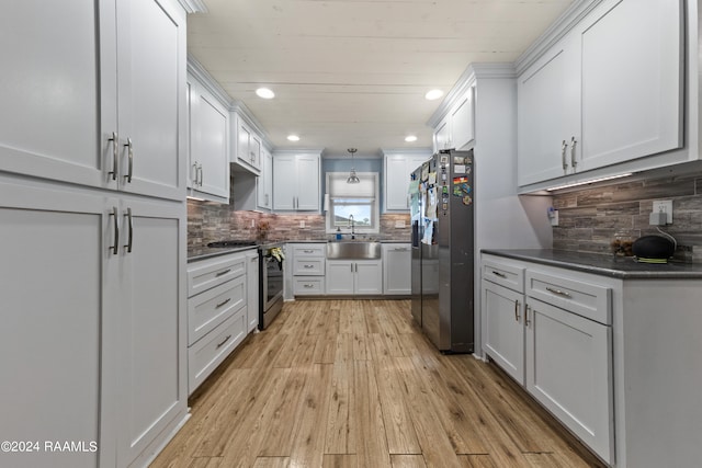 kitchen featuring decorative backsplash, light hardwood / wood-style floors, white cabinets, stainless steel appliances, and sink