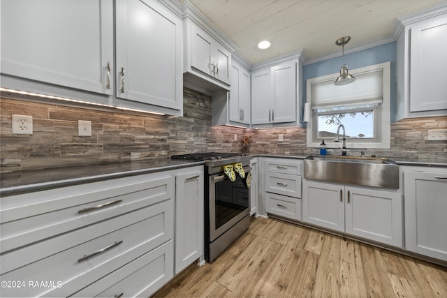 kitchen with decorative backsplash, light hardwood / wood-style floors, stainless steel gas range oven, pendant lighting, and sink