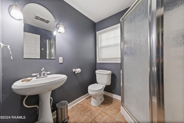 bathroom with tile patterned flooring, a shower with shower door, and toilet