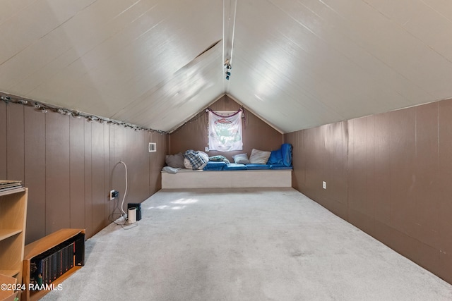 additional living space featuring wooden walls, carpet, and vaulted ceiling