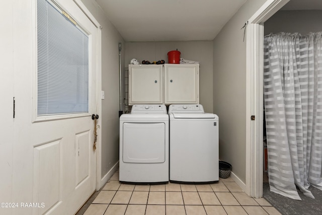 clothes washing area with separate washer and dryer, light tile patterned floors, and cabinets