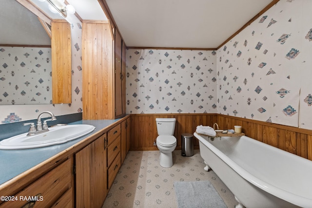 bathroom with a bathing tub, crown molding, vanity, and toilet