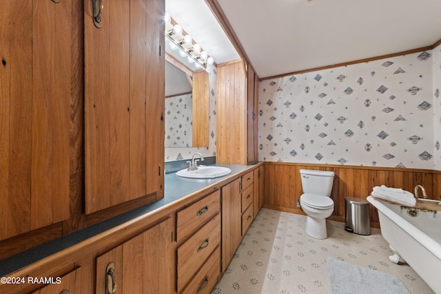 bathroom with a washtub, wood walls, crown molding, vanity, and toilet