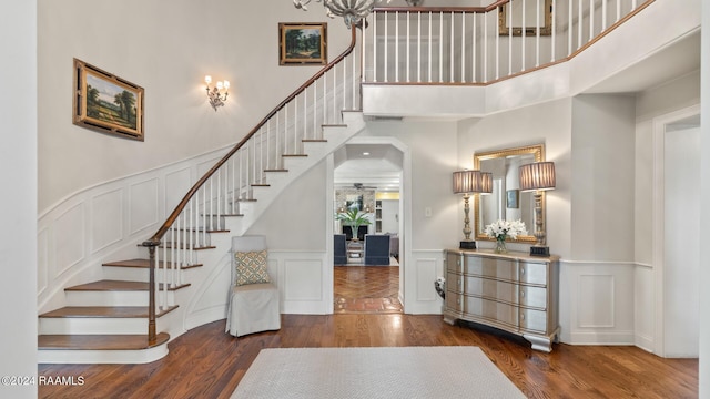 foyer entrance featuring a towering ceiling and dark wood-type flooring