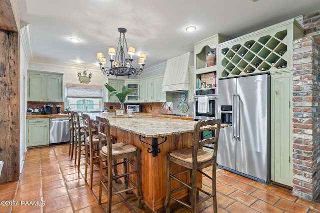 kitchen with pendant lighting, custom exhaust hood, appliances with stainless steel finishes, green cabinets, and decorative backsplash