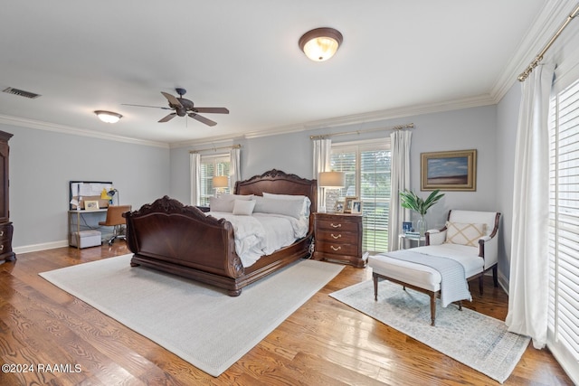 bedroom featuring ceiling fan, hardwood / wood-style flooring, ornamental molding, and multiple windows