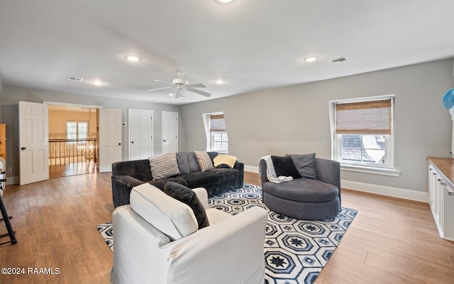 living room with light hardwood / wood-style flooring, ceiling fan, and a wealth of natural light