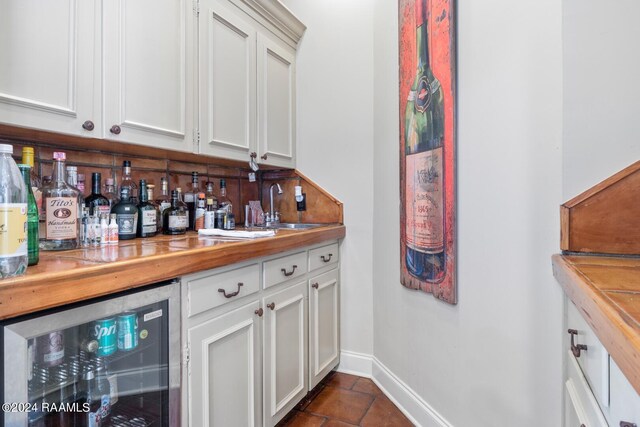 201 Canterbury Rd, Lafayette, LA 70508 - indoor dry bar featuring beverage cooler, baseboards, and dark tile patterned floors